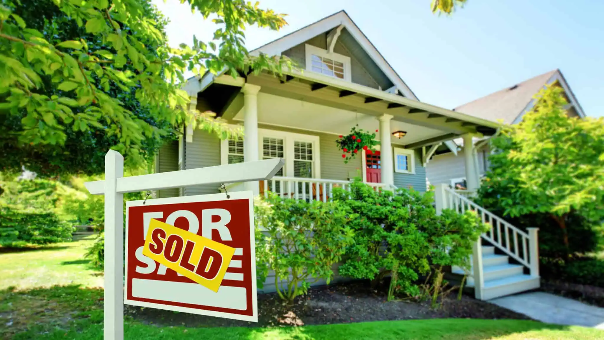 ForSaleJustSold_16x9 A house with a "Sold" sign in front, surrounded by green foliage and trees, listed on Zillow, boasts a charming small front porch and a striking red door.