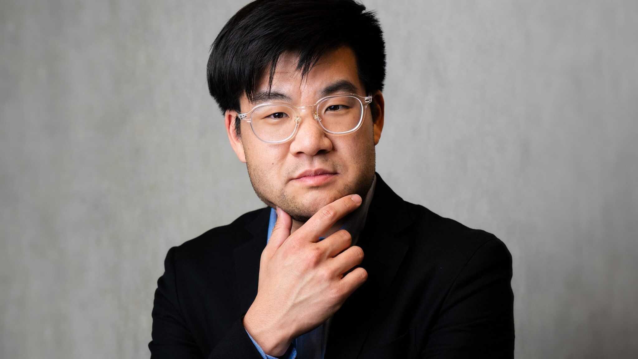 Sam-Cho-1_16x9-min A man in glasses and a black suit appears contemplative with his hand on his chin, uncommonly evoking the essence of thinkers.