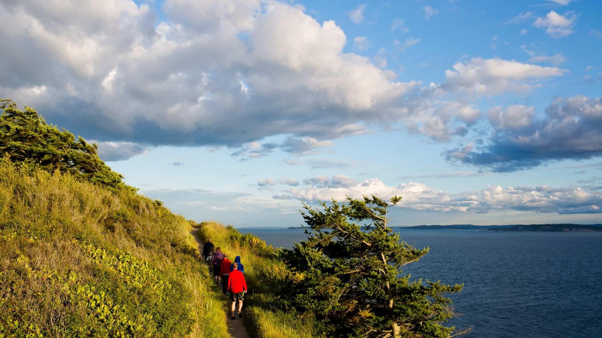 travel-islands-shutterstock_2082937063-16-9-2000x1125-min Hikers on a coastal trail with views of the sea and sky at dusk during an island hopping tour.